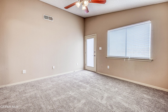 carpeted empty room with ceiling fan, a textured ceiling, visible vents, and baseboards