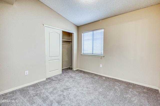 unfurnished bedroom featuring baseboards, carpet, vaulted ceiling, a textured ceiling, and a closet