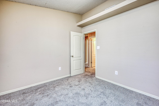 carpeted spare room featuring baseboards and a textured ceiling