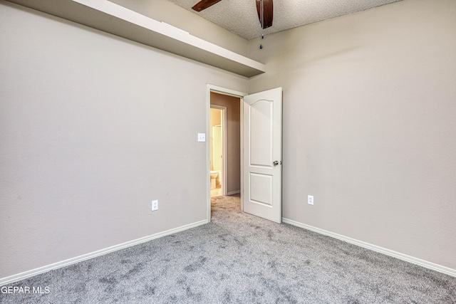 empty room with a ceiling fan, carpet, a textured ceiling, and baseboards