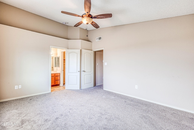 unfurnished bedroom featuring lofted ceiling, light colored carpet, visible vents, connected bathroom, and baseboards