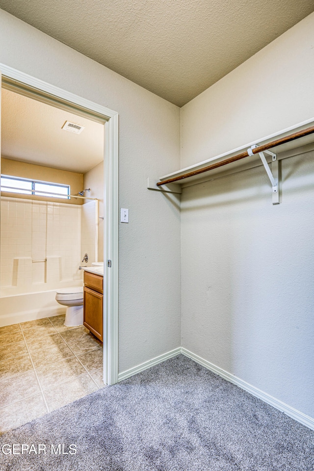 spacious closet with light carpet, light tile patterned floors, and visible vents