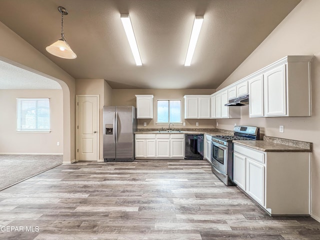 kitchen featuring white cabinets, lofted ceiling, appliances with stainless steel finishes, under cabinet range hood, and a sink