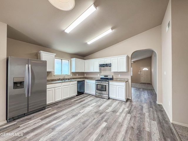 kitchen featuring arched walkways, stainless steel appliances, white cabinetry, vaulted ceiling, and under cabinet range hood