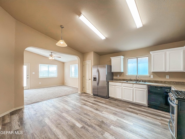 kitchen with arched walkways, lofted ceiling, stainless steel appliances, a sink, and white cabinetry