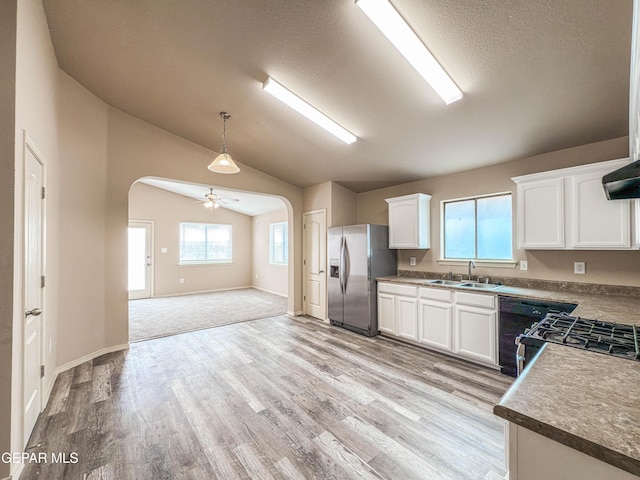 kitchen with arched walkways, lofted ceiling, white cabinets, a sink, and stainless steel fridge with ice dispenser