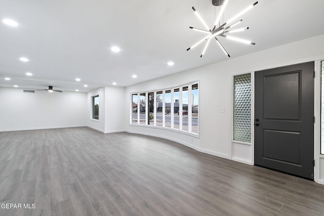 unfurnished living room featuring hardwood / wood-style floors and ceiling fan with notable chandelier