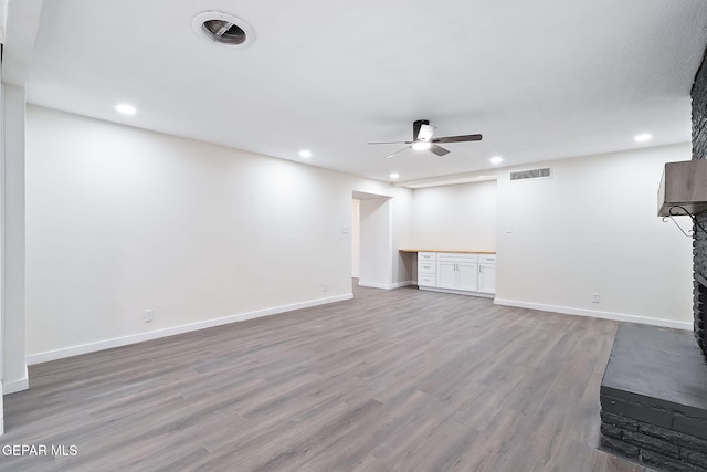 unfurnished living room with ceiling fan, light wood-type flooring, and a fireplace