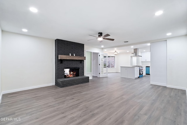 unfurnished living room with a fireplace, light hardwood / wood-style floors, and ceiling fan