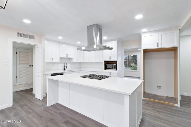 kitchen featuring light hardwood / wood-style flooring, gas stovetop, a kitchen island, white cabinetry, and island exhaust hood