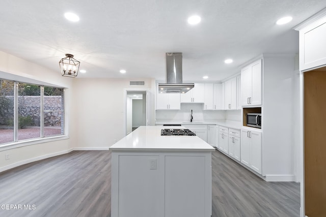 kitchen featuring appliances with stainless steel finishes, island range hood, sink, light hardwood / wood-style floors, and white cabinetry