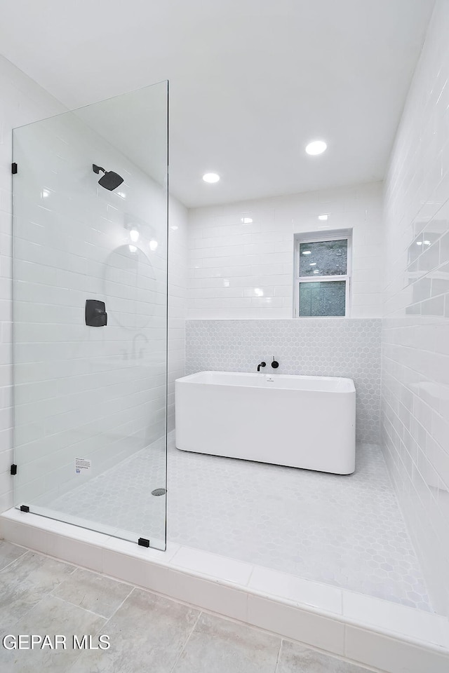 bathroom with tile patterned floors, independent shower and bath, and tile walls