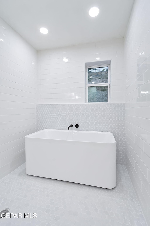 bathroom with a bathtub and tile walls