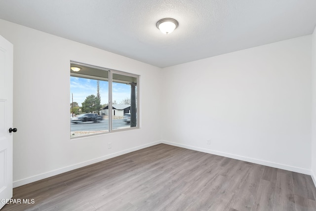 spare room featuring light hardwood / wood-style flooring and a textured ceiling