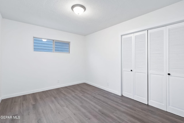 unfurnished bedroom featuring hardwood / wood-style floors, a textured ceiling, and a closet