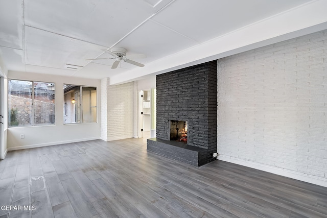 unfurnished living room with wood-type flooring, a brick fireplace, ceiling fan, and brick wall