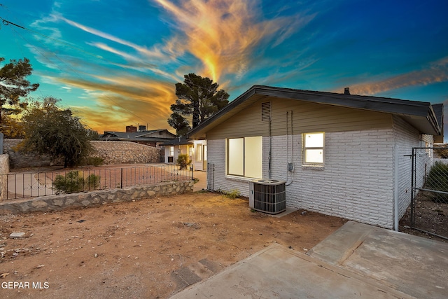 property exterior at dusk with central AC unit and a patio area