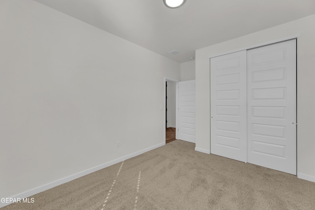 unfurnished bedroom with light colored carpet and a closet