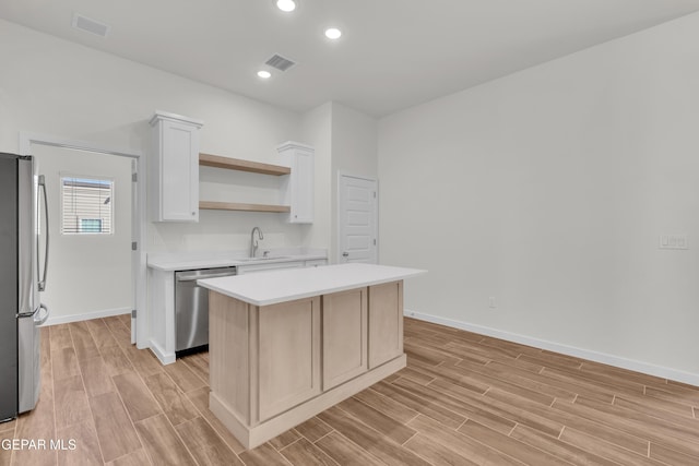 kitchen with white cabinets, a kitchen island, sink, and stainless steel appliances