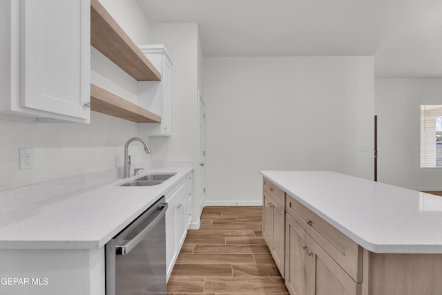 kitchen with light stone countertops, sink, a kitchen island, stainless steel dishwasher, and white cabinets