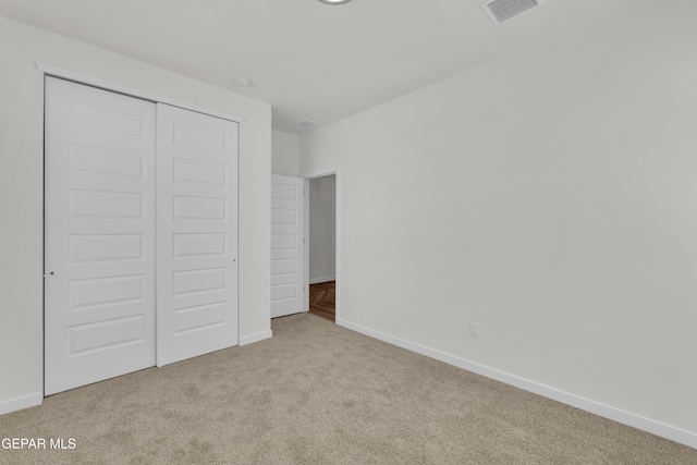 unfurnished bedroom with light carpet and a closet