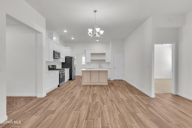 kitchen featuring light wood-type flooring, white cabinetry, stainless steel appliances, and a chandelier