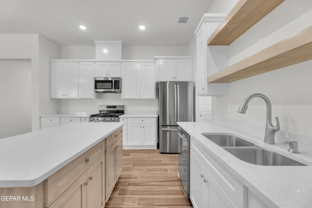 kitchen featuring light stone countertops, appliances with stainless steel finishes, sink, white cabinets, and a center island