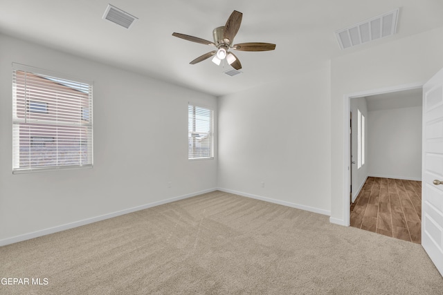 spare room with ceiling fan and light carpet