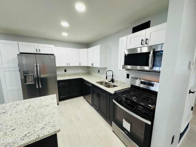 kitchen with white cabinets, sink, light wood-type flooring, light stone counters, and stainless steel appliances