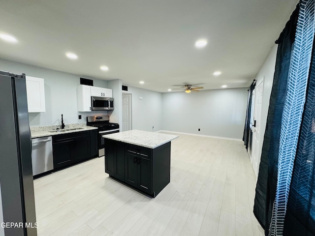 kitchen with white cabinets, a barn door, light hardwood / wood-style floors, appliances with stainless steel finishes, and a kitchen island