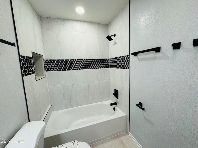 bathroom featuring tiled shower / bath combo and toilet