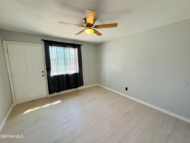 empty room featuring a textured ceiling, light hardwood / wood-style floors, and ceiling fan