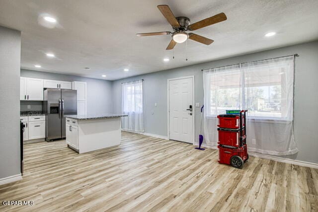 kitchen with plenty of natural light, white cabinetry, stainless steel refrigerator with ice dispenser, and light hardwood / wood-style flooring