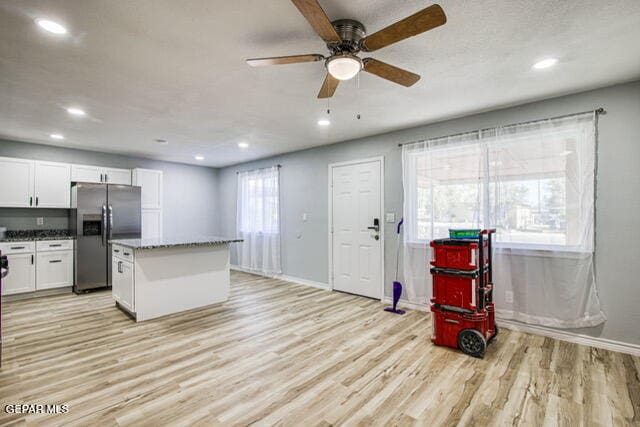 kitchen with stainless steel fridge, white cabinetry, and a wealth of natural light