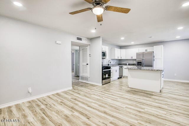 kitchen with white cabinets, appliances with stainless steel finishes, light wood-type flooring, and a kitchen island