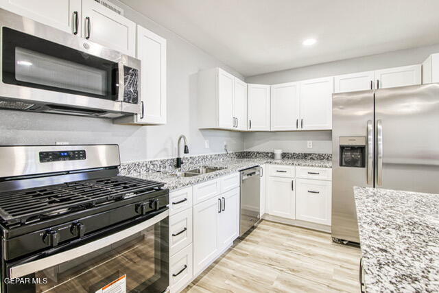 kitchen with white cabinets, appliances with stainless steel finishes, and light stone countertops