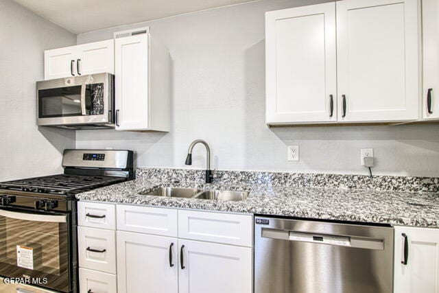 kitchen featuring light stone counters, sink, white cabinetry, and stainless steel appliances