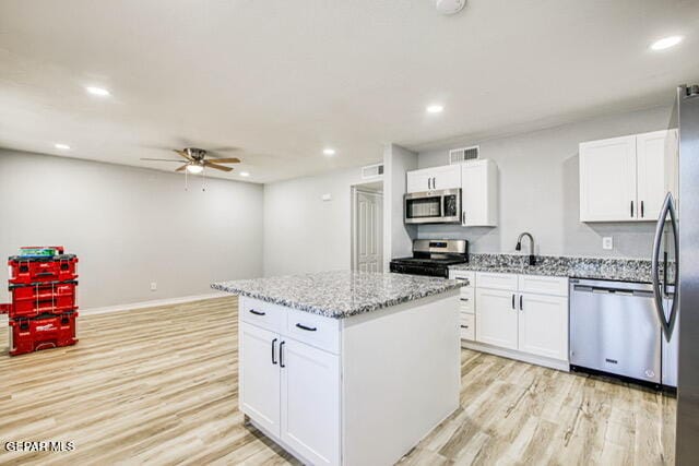 kitchen with white cabinetry, a center island, stainless steel appliances, and light hardwood / wood-style flooring