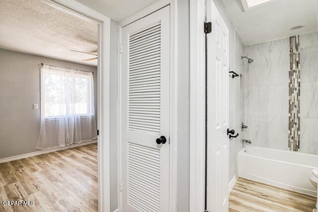 bathroom featuring toilet, ceiling fan, hardwood / wood-style floors, and tiled shower / bath