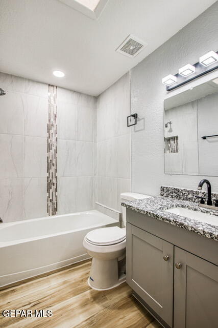 full bathroom with vanity, toilet, wood-type flooring, and tiled shower / bath combo