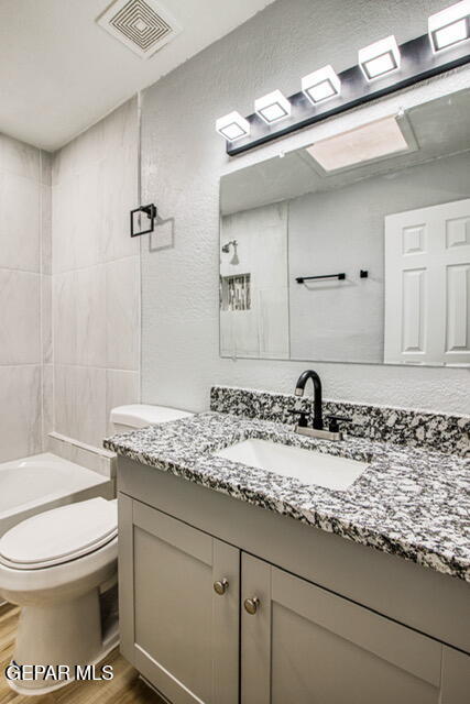 full bathroom with hardwood / wood-style floors, vanity, toilet, and tiled shower / bath combo