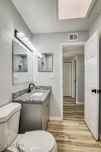 bathroom featuring vanity, hardwood / wood-style flooring, and toilet