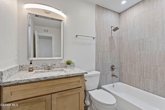 full bathroom featuring vanity, tiled shower / bath combo, and toilet