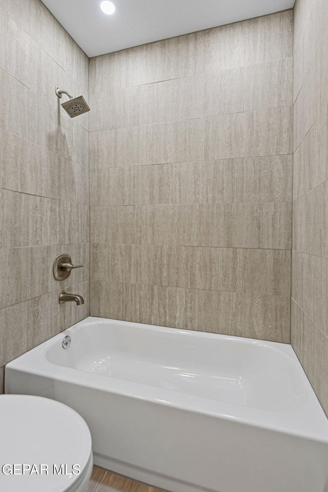 bathroom with toilet and tiled shower / bath