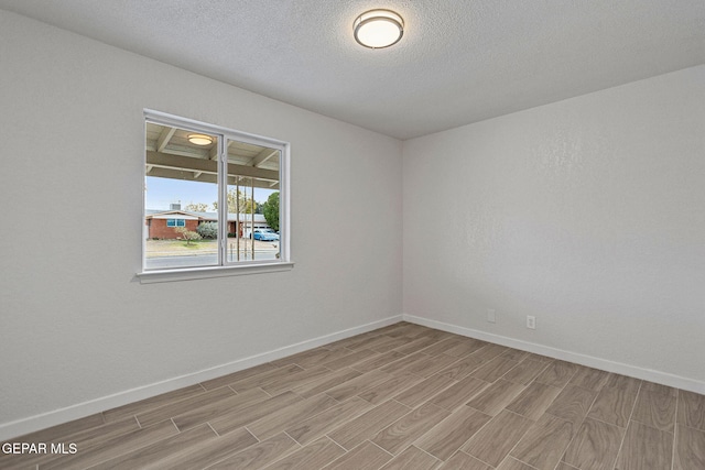 empty room with a textured ceiling and light wood-type flooring