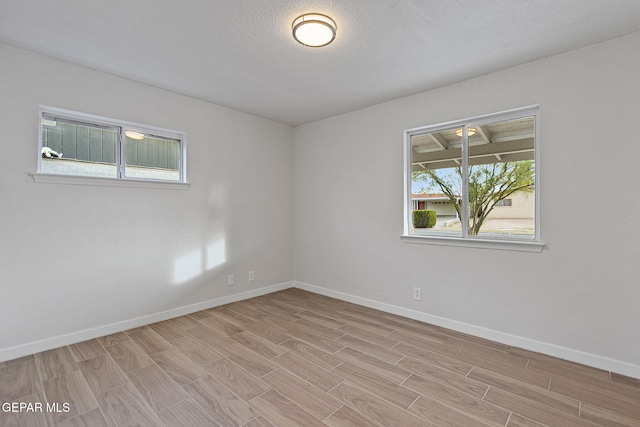 empty room with light hardwood / wood-style flooring and a textured ceiling