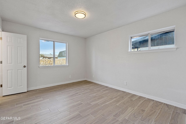 unfurnished room with light wood-type flooring and a textured ceiling