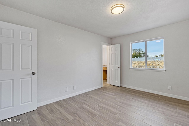 empty room featuring light wood-type flooring and a textured ceiling