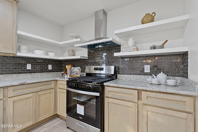 kitchen with light stone countertops, light brown cabinets, stainless steel range with gas cooktop, and wall chimney range hood