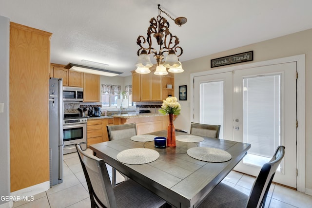 dining room featuring light tile patterned floors, a notable chandelier, and sink